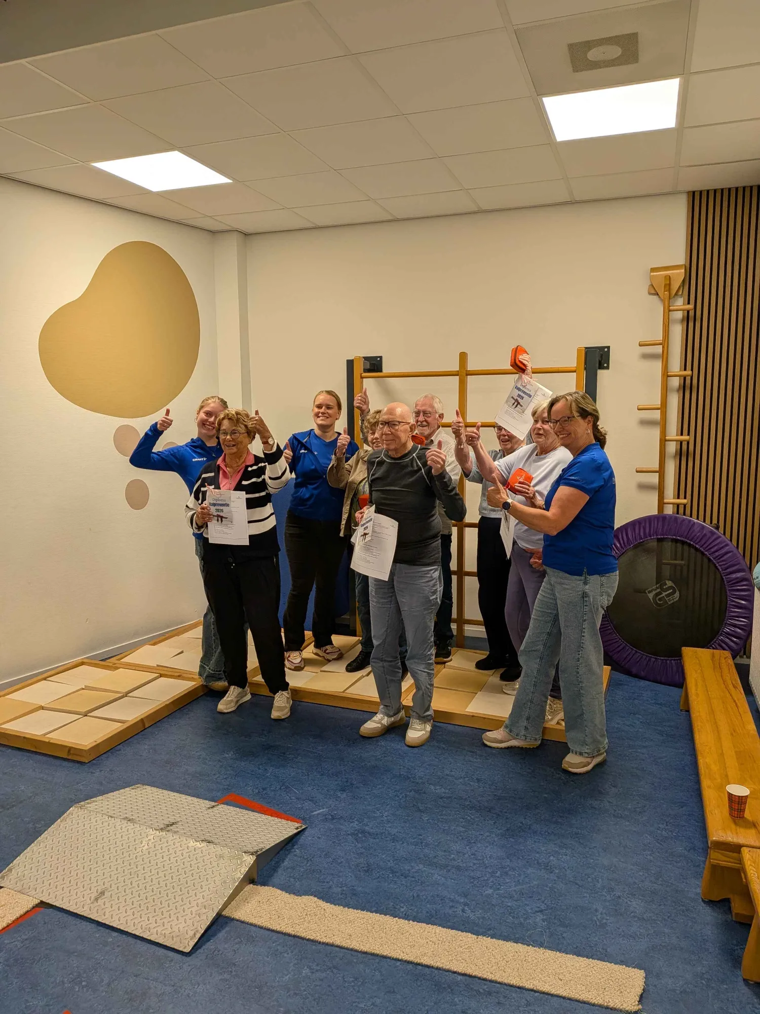 Participants and physiotherapists of the fall prevention programme with their diplomas in the practice gym